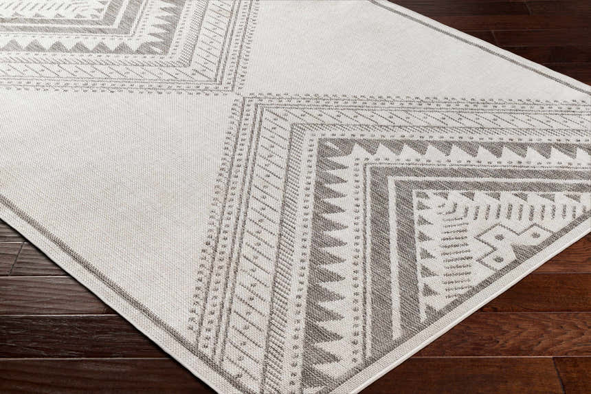 Close up of the Deana Light Gray Area Rug showing its geometric, tribal-inspired pattern and woven texture. Corner