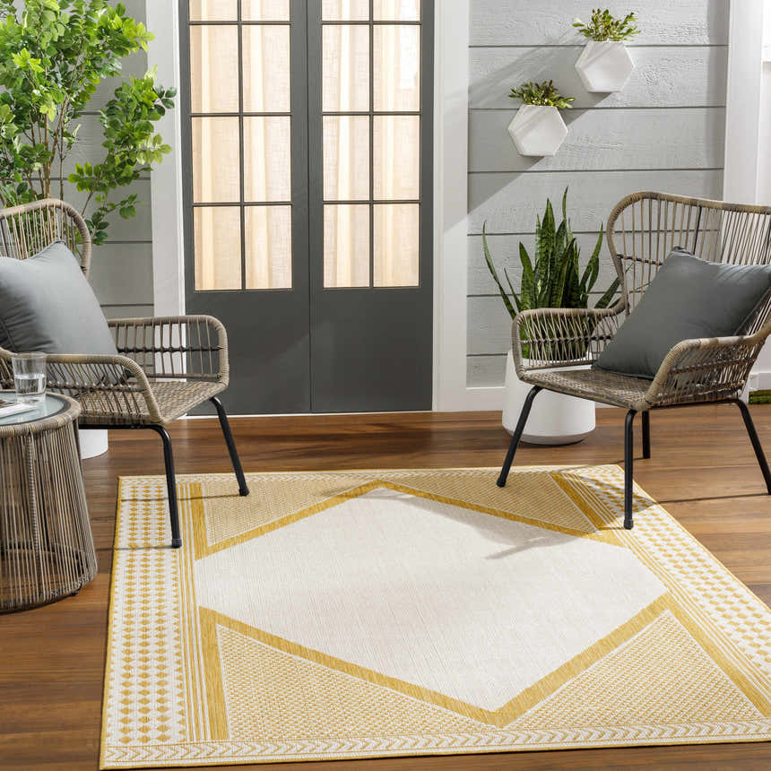 Outdoor patio scene with Efrem Mustard Area Carpet, wicker chairs, and potted plants. Roomscene-Rectangle