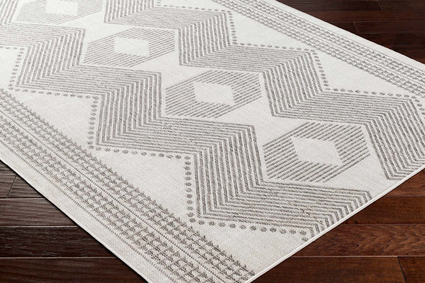Close-up of the Evana Gray Area Rug showing its geometric pattern, light gray and off-white colors, and woven texture. Corner