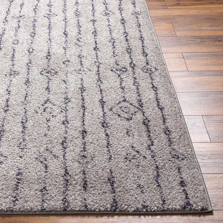 Close-up of the Demi Gray Washable Area Rug showing its shag texture and dark brown vertical line pattern on wood floors. Front