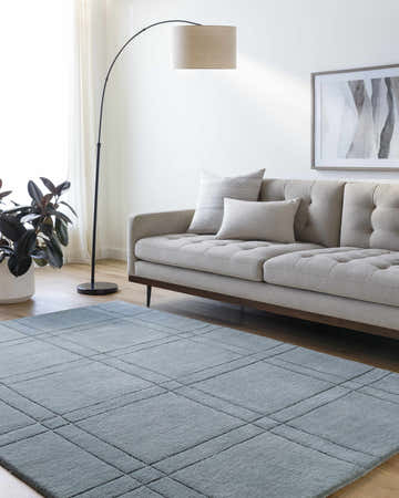 Living room scene with a sage Sixto Area Rug, light gray sofa, floor lamp, and modern art. Roomscene-Rectangle