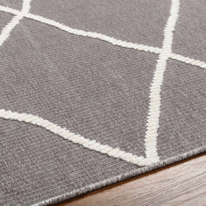 Close-up of Amani Gray Washable Rug. Features a dark gray base with a geometric white thatch pattern. Contemporary style. Texture