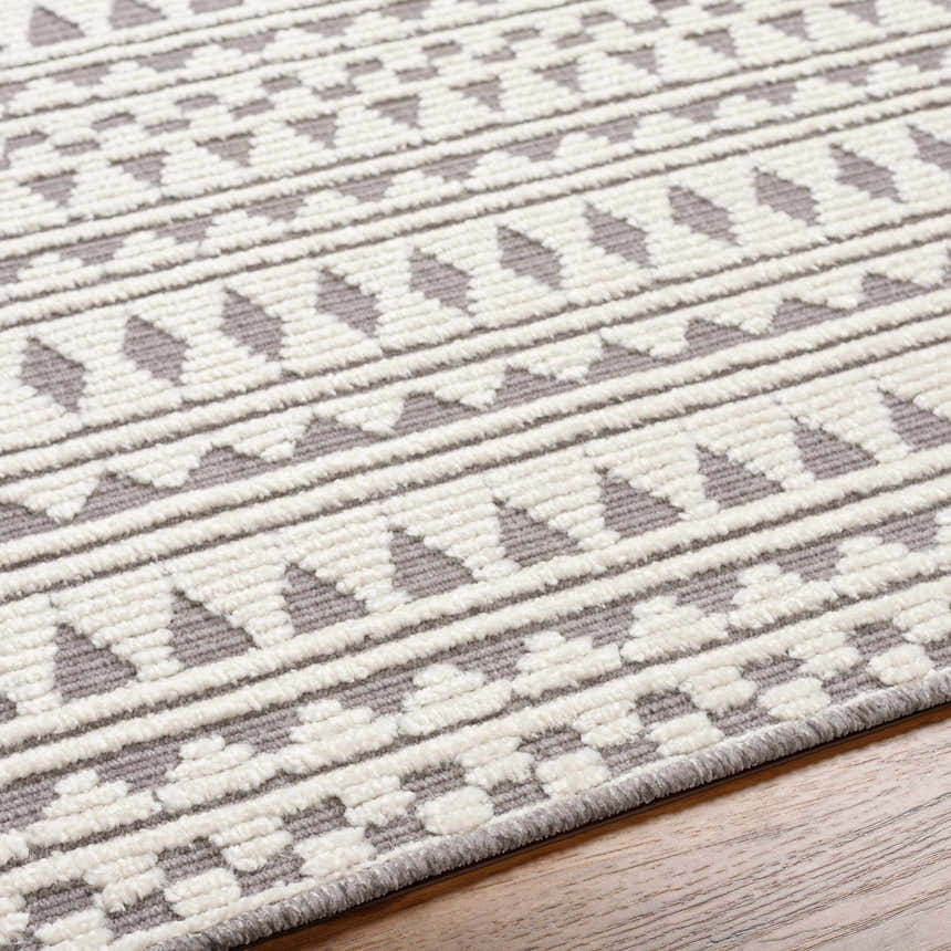 Close-up of the Cili Washable Area Rug in cloud gray and light gray with a geometric pattern. Machine woven texture. Texture