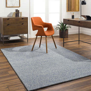 Home office with Alyra Light Blue rug, wood floors, desk, orange chair, and natural light from a window. Roomscene-Rectangle