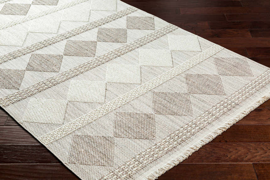 Close-up of the Igone Area Rug showing a geometric square pattern in beige and brown on dark wood flooring. Corner