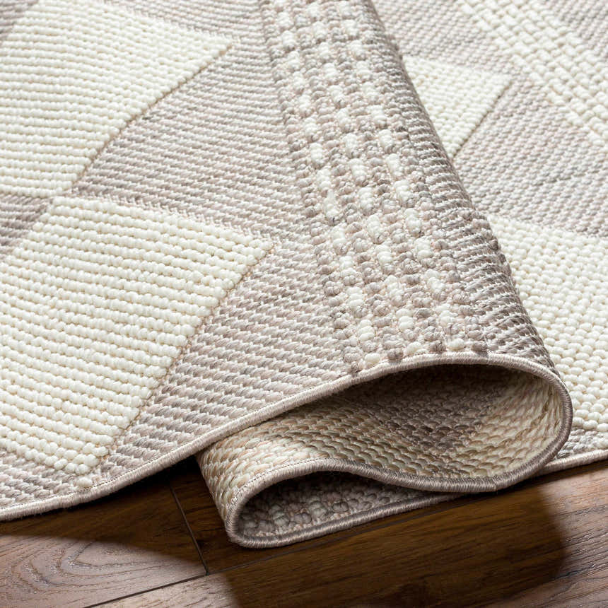 Close-up of the Igone Area Rug showing its beige, gray, and brown geometric pattern and textured, machine-woven construction. Fold