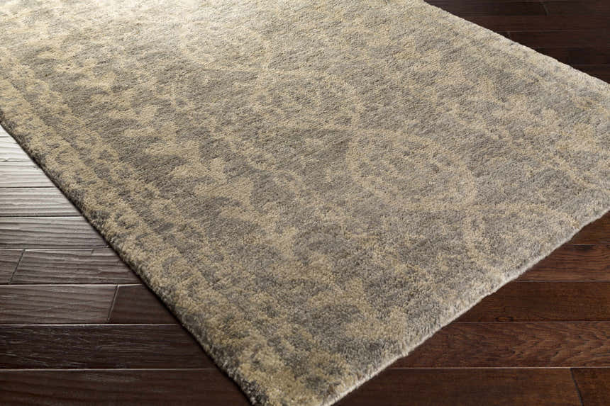 Close-up of the Sonnette Jute Rug in brown, gray and ivory on a dark wood floor. Hand-knotted farmhouse style. Corner