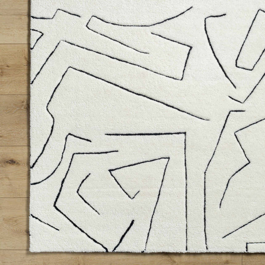 Close-up of the Mony Rose Cream Area Rug showing its cream wool texture and black geometric line design. Corner