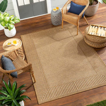 Outdoor patio scene with the beige Amora Flatweave Faux Jute Rug, wicker chairs, and potted plants on a wood deck. Roomscene-Rectangle