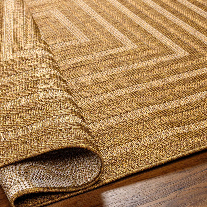 Close-up of the Dyami Flatweave Faux Jute Rug in camel and brown, showing the geometric pattern and woven texture. Fold