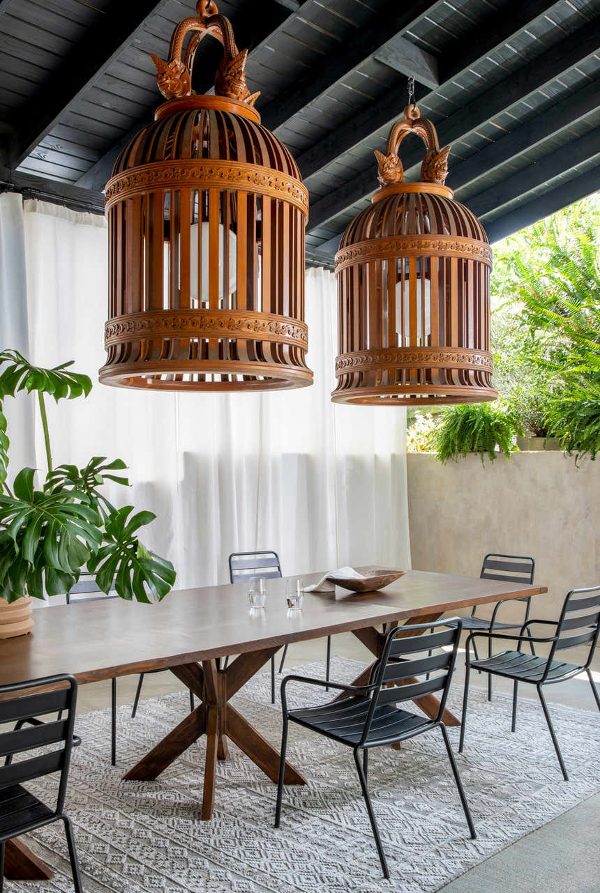 Dining room scene with a gray Kazi Area Rug under a wood table and black chairs, with decorative wood lamps. Roomscene-Rectangle