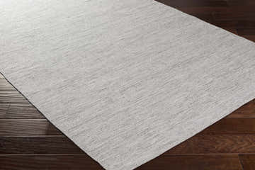 Close-up of the hand-woven Spragueville rug in black and white, showing the natural fiber texture on dark wood flooring. Corner