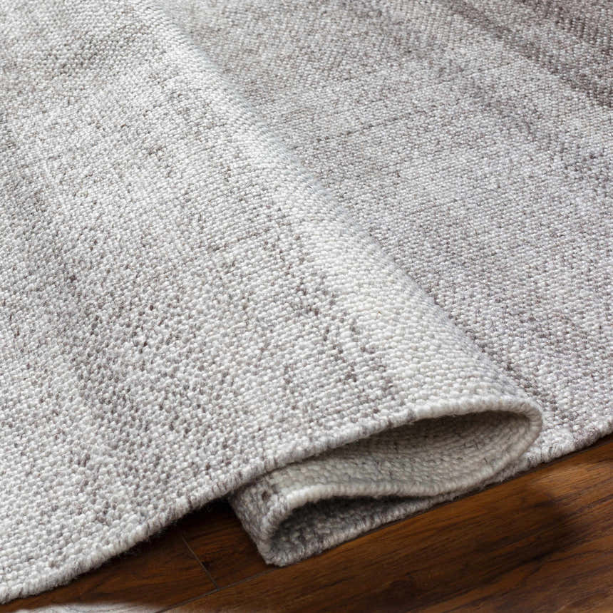 Close-up of the Fiora Area Rug showing its hand-woven texture and multi brown and gray tones. Fold