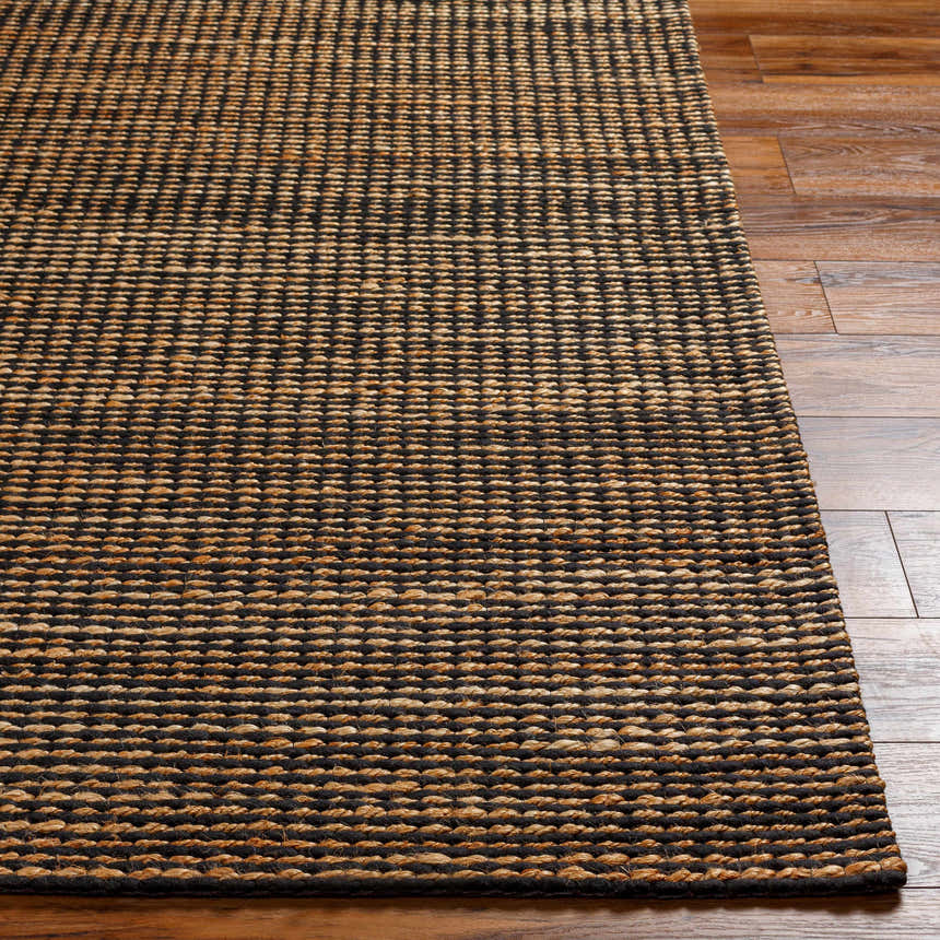 Close-up of the hand woven Riki Black Area Rug, showcasing its jute texture and contemporary black and tan design. Front