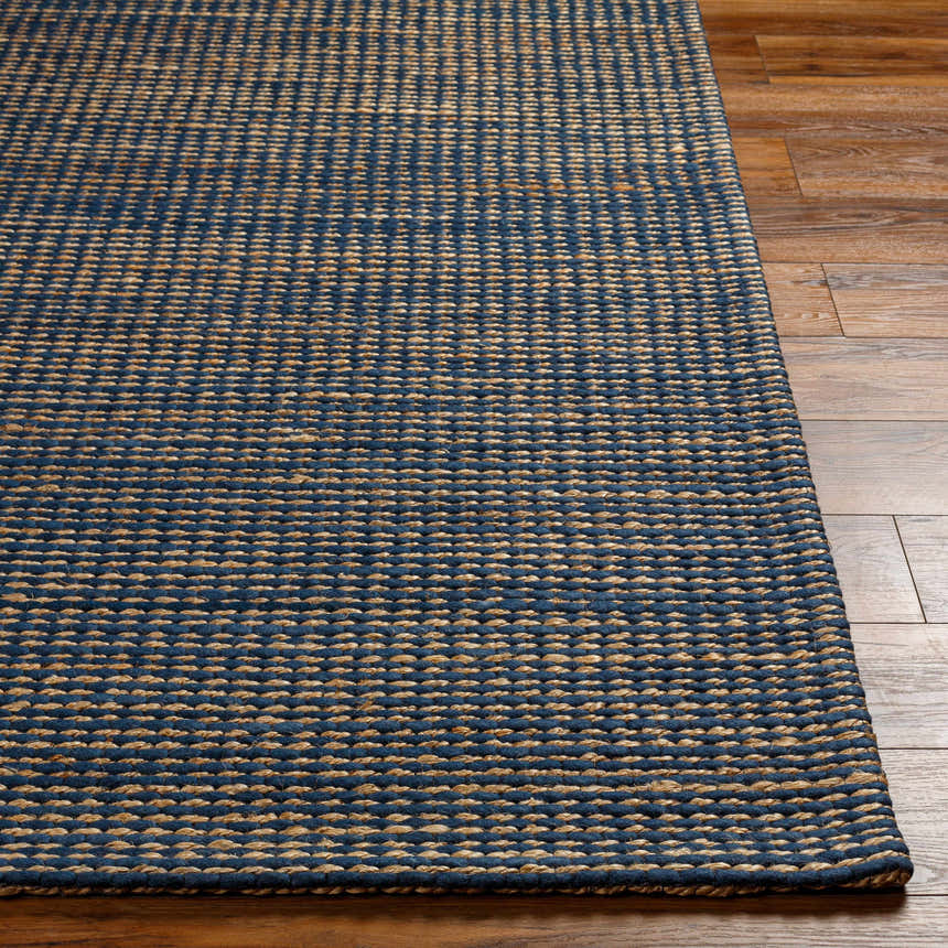 Close-up of the hand woven Riki Navy Area Rug showing its navy and beige textured pattern on wood floor. Front