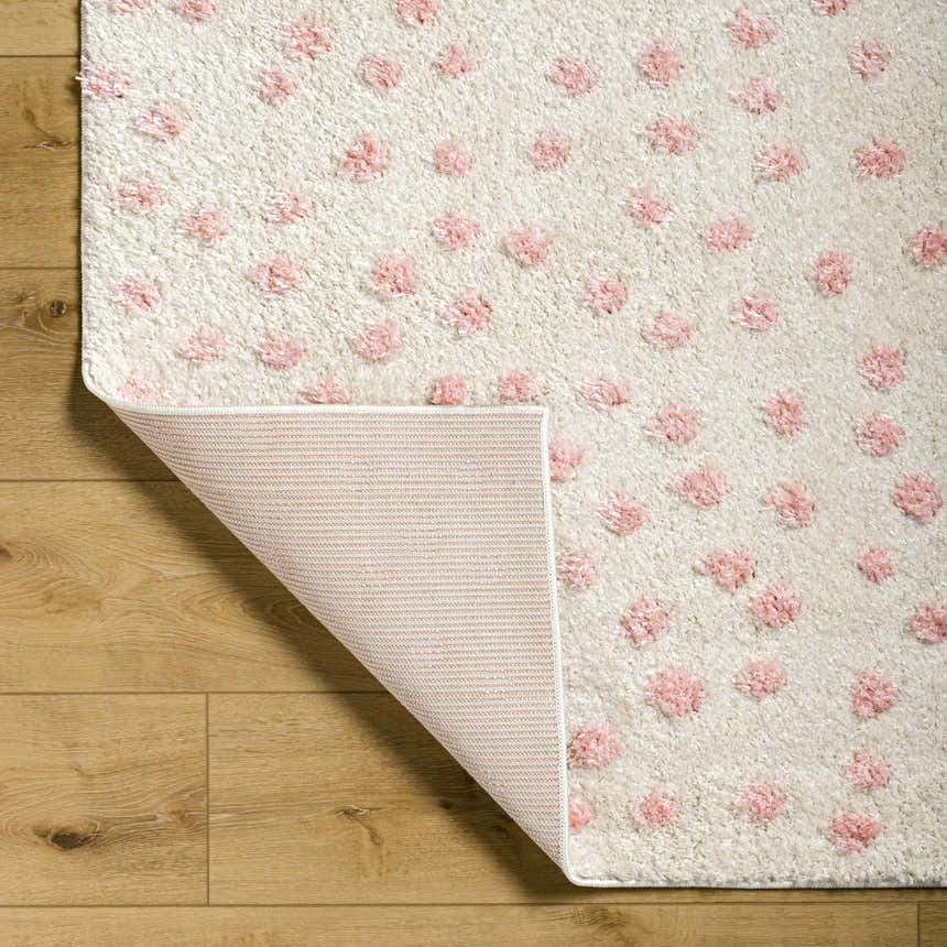 Close-up of Bernt Beige Area Rug. Beige shag rug with pale pink tufted polka dot pattern. Shows rug backing. Fold