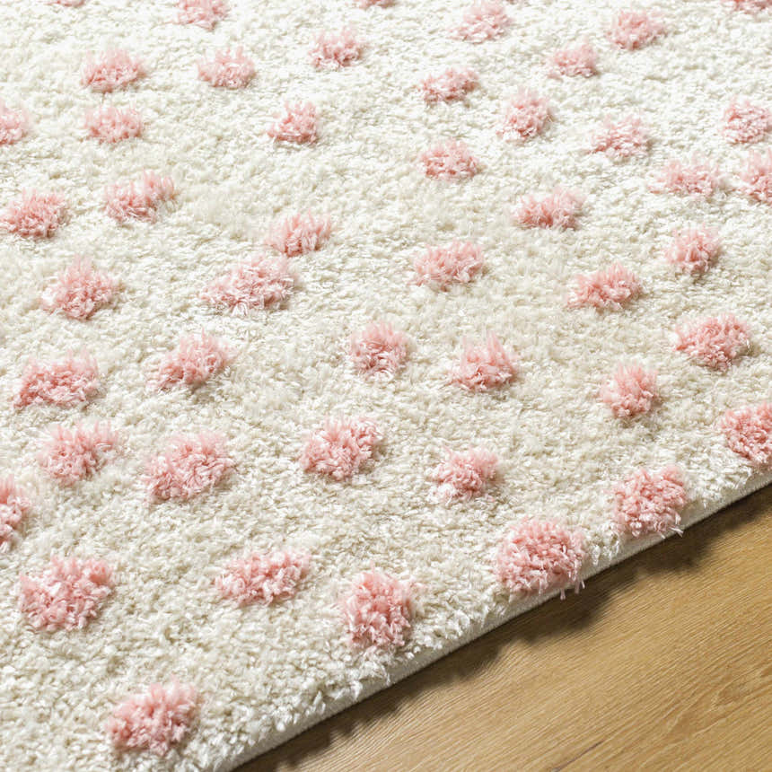 Close-up of Bernt Beige Area Rug with a textured beige base and pale pink tufted dot pattern. Texture