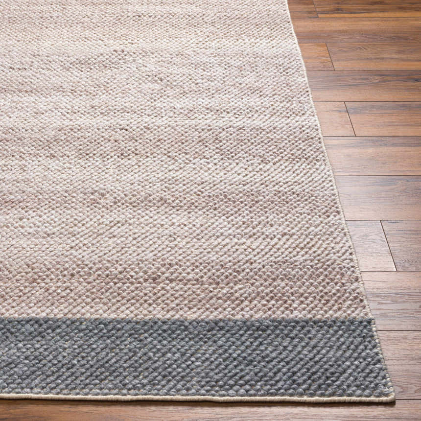 Close-up of the hand woven Edwin Area Rug. The rug is lambswool, light brown, and gray with a dark gray border. Front