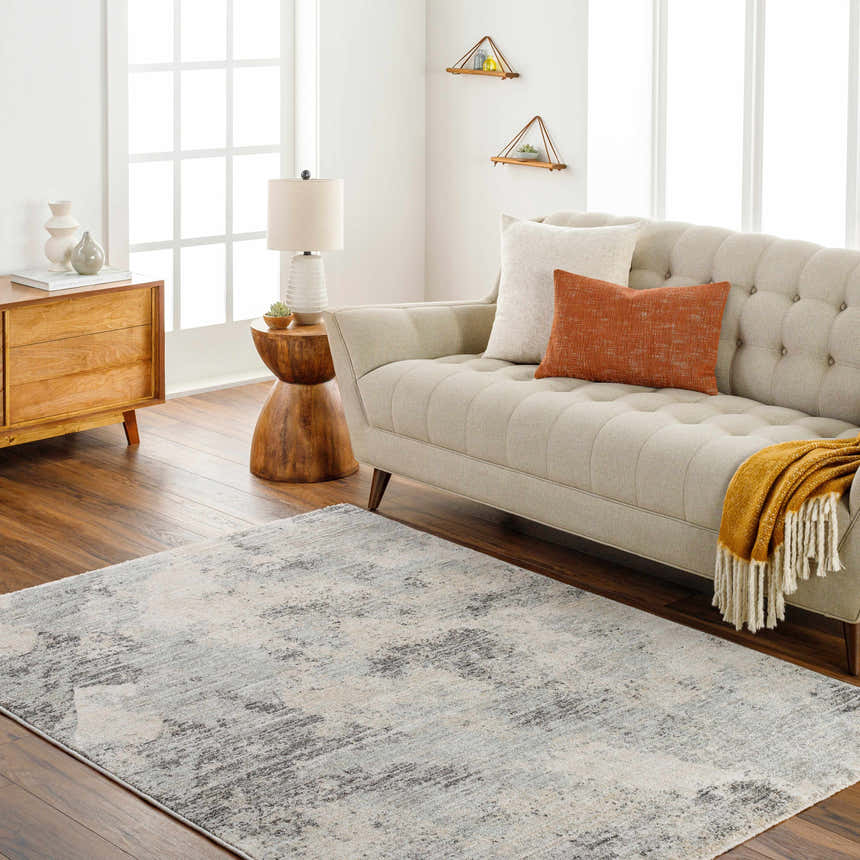 Living room scene with a beige sofa, wooden furniture, and the Gatik Area Rug in beige and gray tones. Roomscene-Rectangle