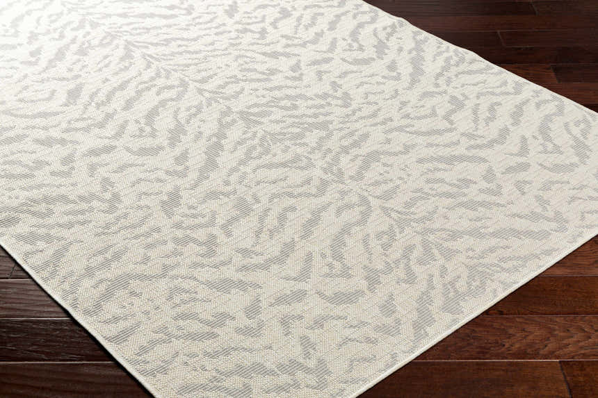 Close-up of Friso Cream Area Rug showing beige and gray contemporary pattern and woven texture on dark wood floor. Corner