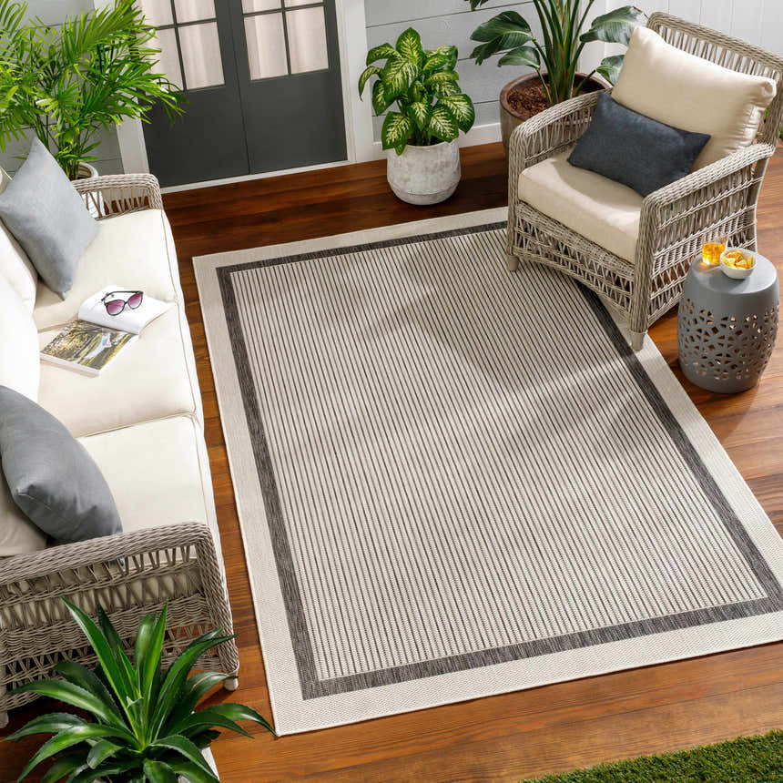 Outdoor patio scene with Hevel Black & White Area Rug, wicker furniture, wood floor, and potted plants for a relaxing vibe. Roomscene-Rectangle