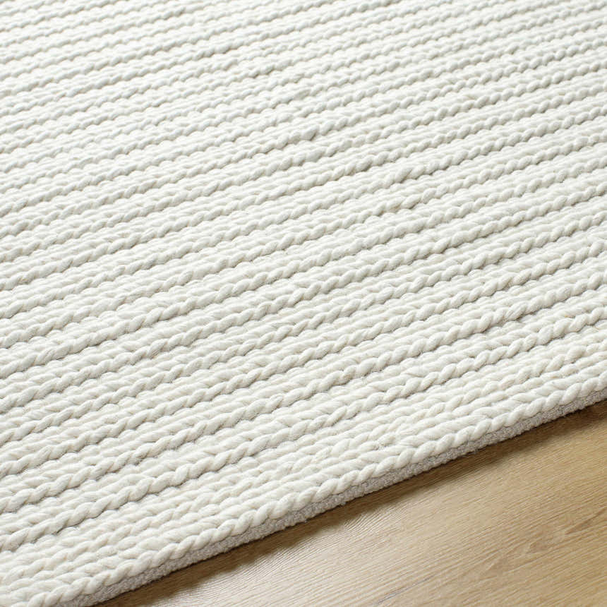 Close-up of the hand woven Lenci Rose Cream Area Rug, showing its beige, ivory, and rose cream braided texture. Texture