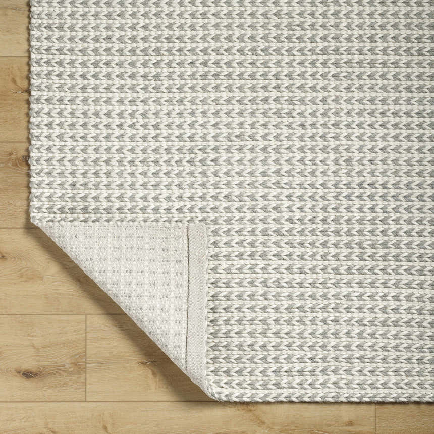 Close-up of the Lenci Bone Area Rug showing its hand woven texture and contemporary beige and bone arrow pattern. Fold