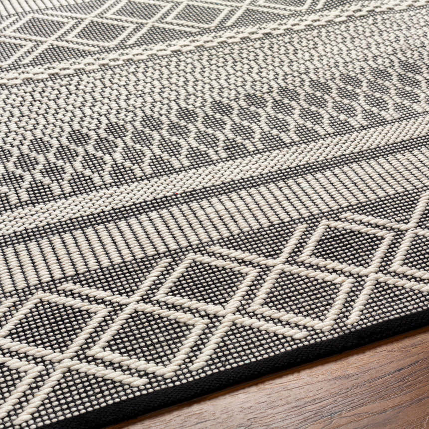 Close-up of the hand woven Hala Area Rug. Dark gray and off white geometric pattern, contemporary style. Texture