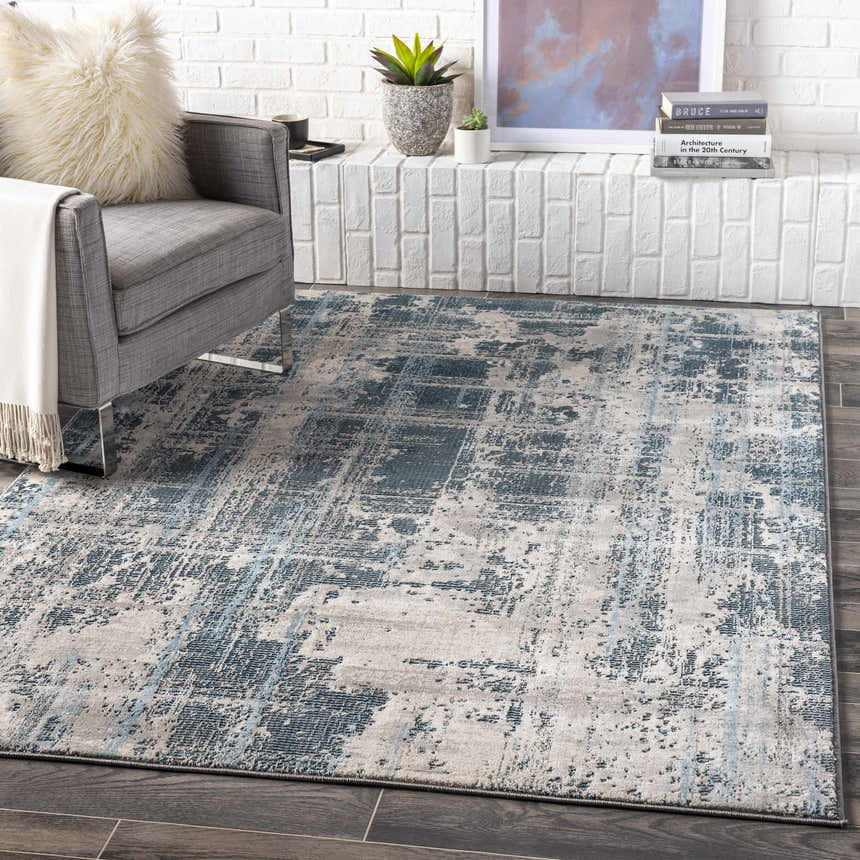 Living room scene with gray chair and Stokenchurch Area Carpet in blue, gray, and white abstract design. Roomscene-Rectangle