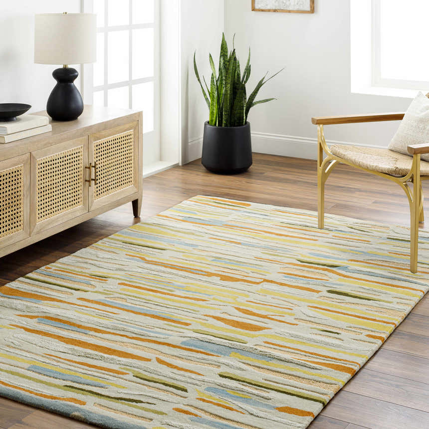 Living room scene with Aram Area Rug. Contemporary style with bronze, camel, and gray tones. Wood floors, cane cabinet, and modern chair. Roomscene-Rectangle