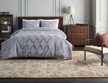 Bedroom scene with a Conesus Hand Tufted Tan 1012 Area Rug, gray bedding, and wooden furniture. Traditional style. Roomscene-Rectangle