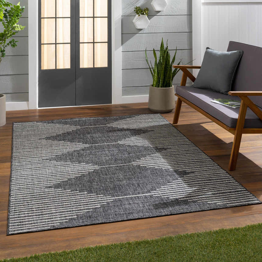 Outdoor patio scene with a black and cream Stephan Area Rug, gray sofa, and wood flooring. Roomscene-Rectangle