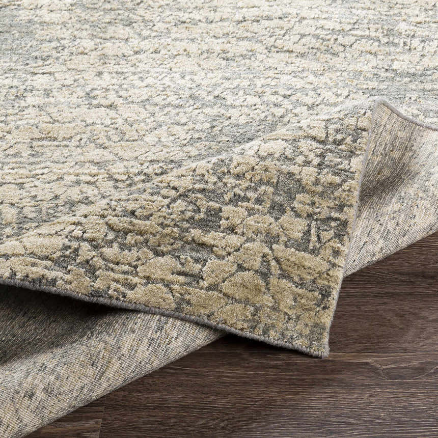Close-up of the Streatley Area Rug showing its beige, gray, and black contemporary design and hand-knotted texture. Fold