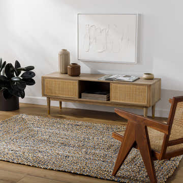 Living room scene with a Druce Area Rug in medium brown and blue tones, styled with a wood media console and chair. Roomscene-Rectangle