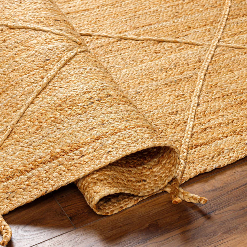 Close-up of the hand-woven Zeno Area Rug. Natural jute rug in tan and brown tones with a braided diamond pattern. Fold