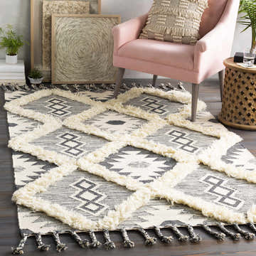 Living room scene with a Sultan Charcoal/Beige Tribal Tassel Wool Rug, pink chair, and bohemian decor. Roomscene-Rectangle