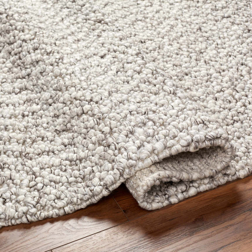 Close-up of the hand woven Chole Area Rug in natural gray, nutmeg, and smoke colors showing texture. Fold