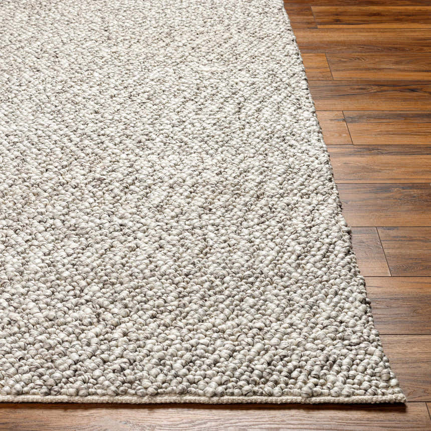 Close-up of the hand-woven Chole Area Rug in natural gray on a wood floor. Recycled PET yarn rug texture. Front