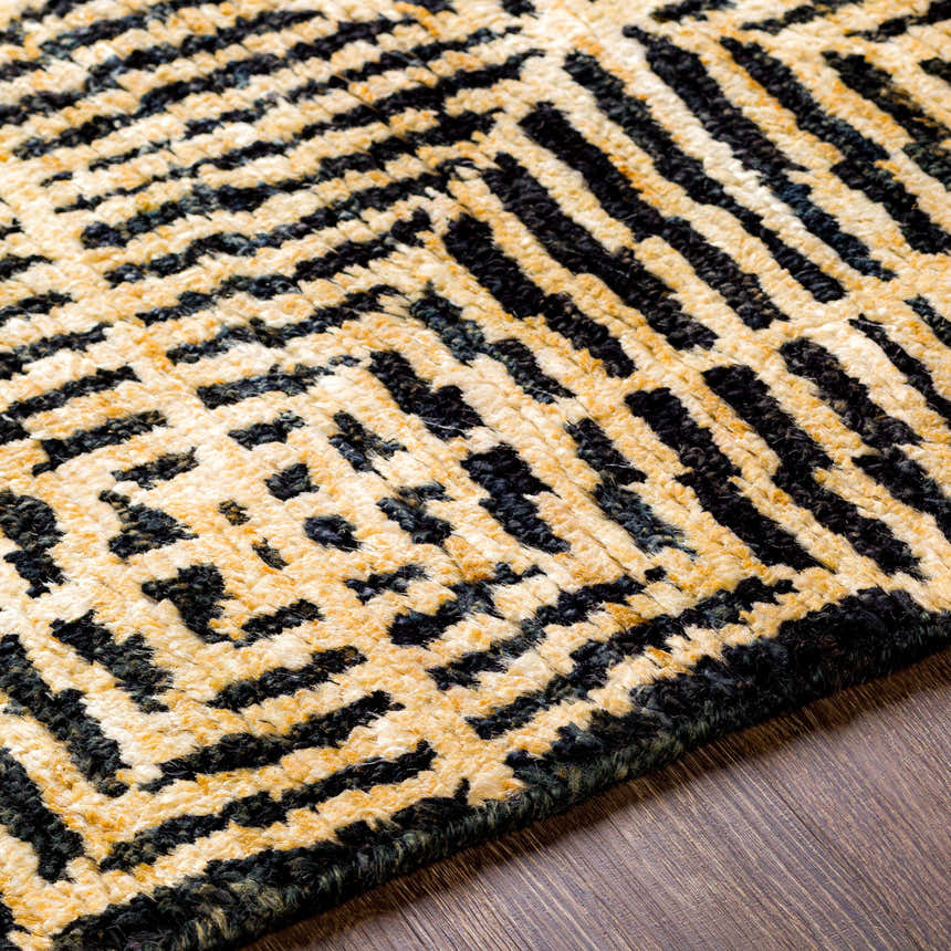 Close-up of the Swainsboro Jute Rug. Beige and black geometric pattern. Hand-knotted texture on wood floor. Texture
