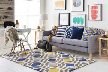 Living room scene with a gray sofa and the Taneytown area rug, a contemporary wool rug with blue, yellow, and gray geometric patterns. Roomscene-Rectangle