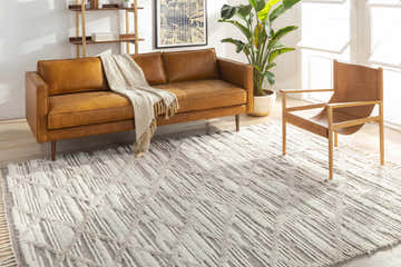 Living room scene with a brown leather sofa and the light beige Tankerton Area Rug. Roomscene-Rectangle