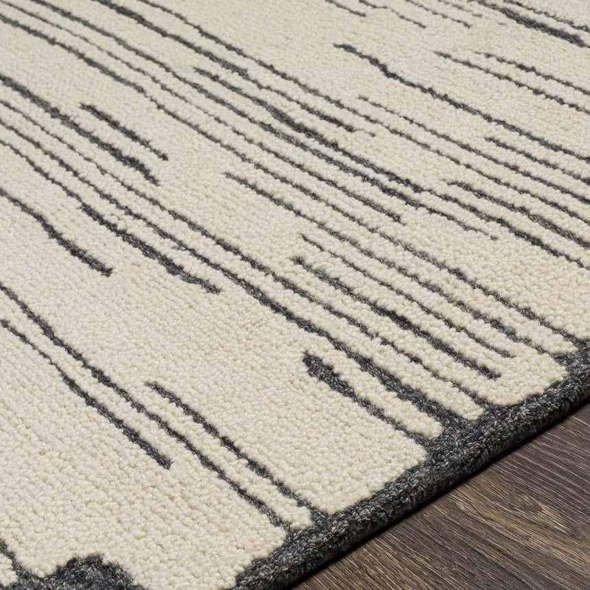 Close-up of the hand-tufted Tapas Wool Area Rug, showing its cream base and charcoal striped pattern and wool texture. Texture