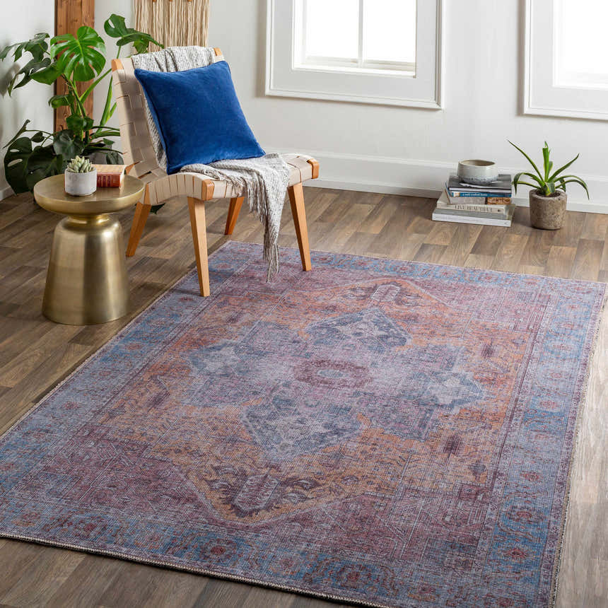 Living room scene with Otaki Purple & Brown Washable Area Rug, chair with blue pillow, gold side table, and plants. Roomscene-Rectangle