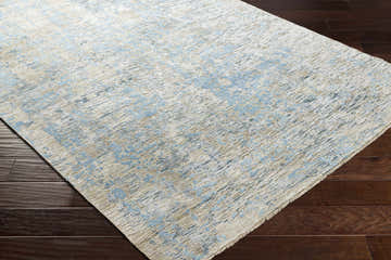 Close-up of the Temora Area Rug. Contemporary design in blue, ice blue, light gray, and taupe on dark wood floors. Corner