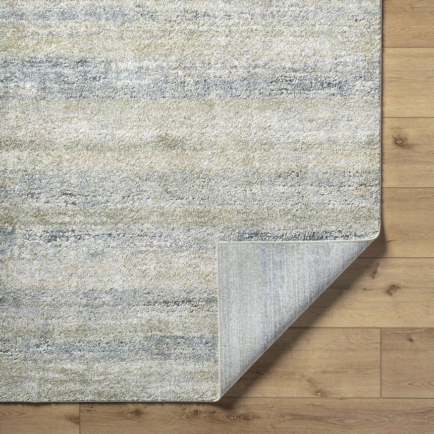 Close-up of the Taran Thick Luxe Rug showing light gray, olive, peach, and tan textured design on wood floor. Fold