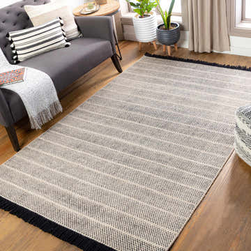 Living room scene with a beige and black striped Thorold Area Rug, gray sofa, and wood floors. Roomscene-Rectangle