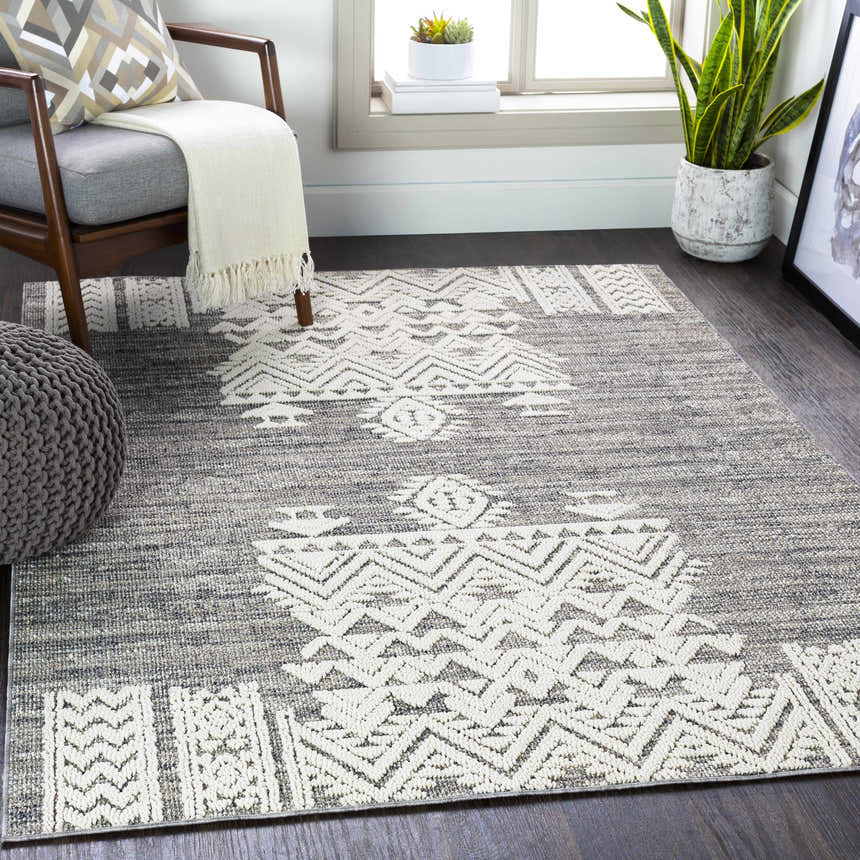 Living room scene with gray chair, pouf, and Thorntonville Outdoor Rug in black, gray, and white. Roomscene-Rectangle
