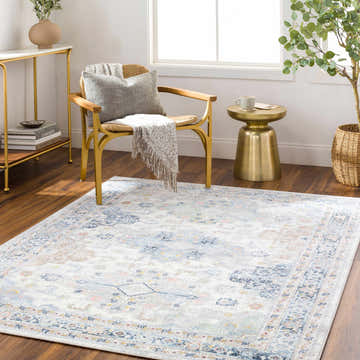 Living room scene with a Tana Washable Area Rug in arctic stone, gold accents, and a light, airy feel. Roomscene-Rectangle