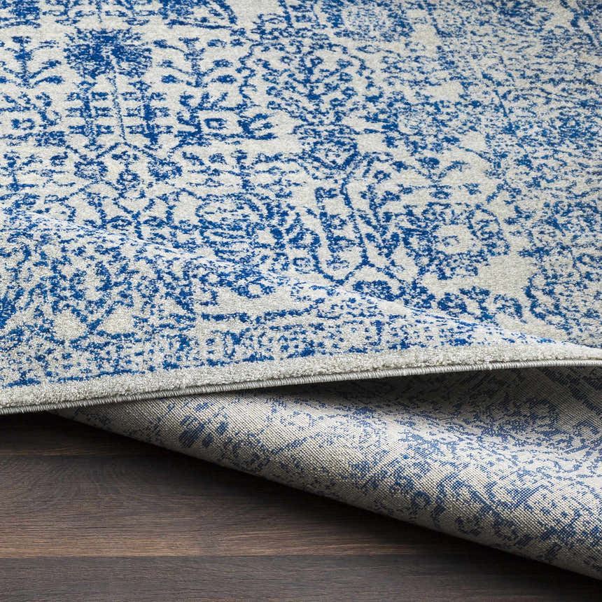 Close-up of the Truxton Area Rug, showcasing its light beige and navy bohemian pattern and machine-woven texture. Fold