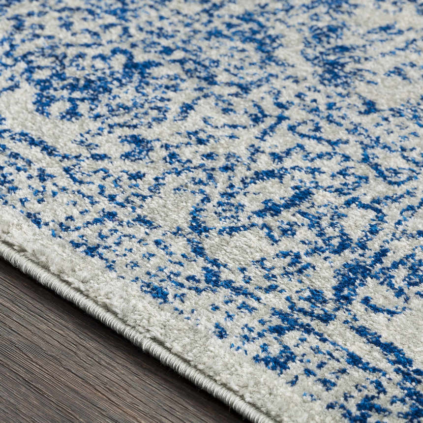 Close-up of the Truxton Area Rug showing its light beige and navy vintage-style pattern and soft texture. Texture